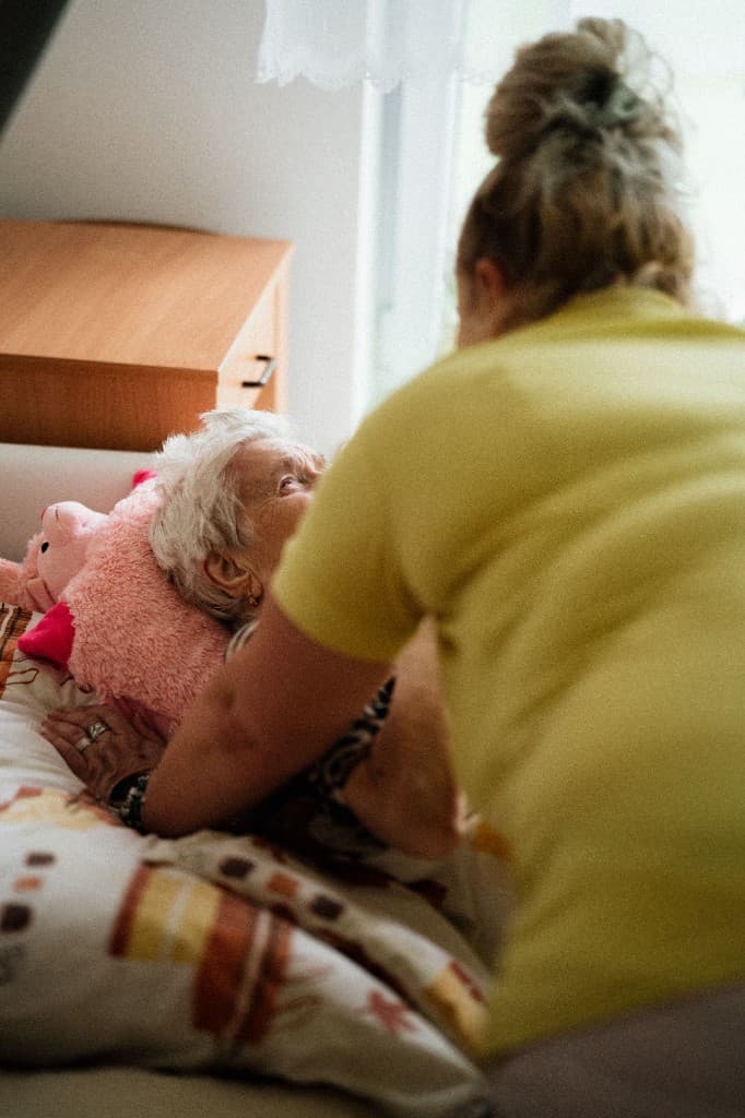 A carer offering gentle, dignified support at the bedside