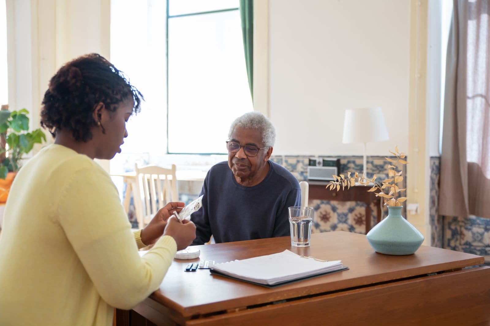 A care professional discussing support needs with an older adult at a bright home table